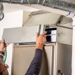 HVAC tech opening a furnace panel to diagnose why the furnace is blowing cold air